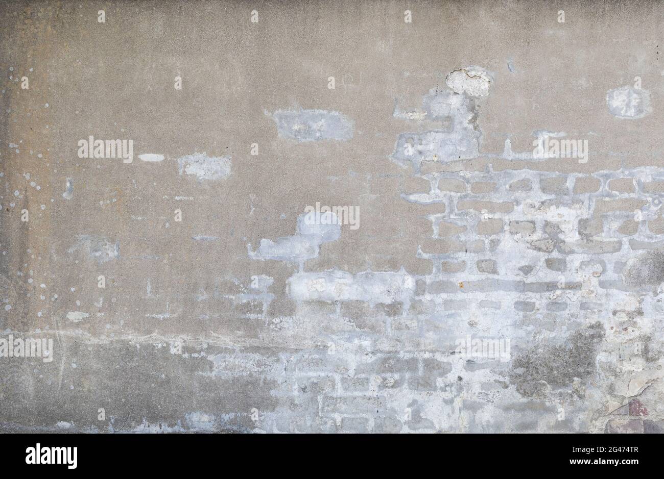 Vorderansicht einer alten, schmutzigen, beschädigten und verputzten Wand. Der Putz ist teilweise abgeschält und zeigt alte Ziegelsteine. Hochauflösender texturierter Hintergrund im Vollformat Stockfoto