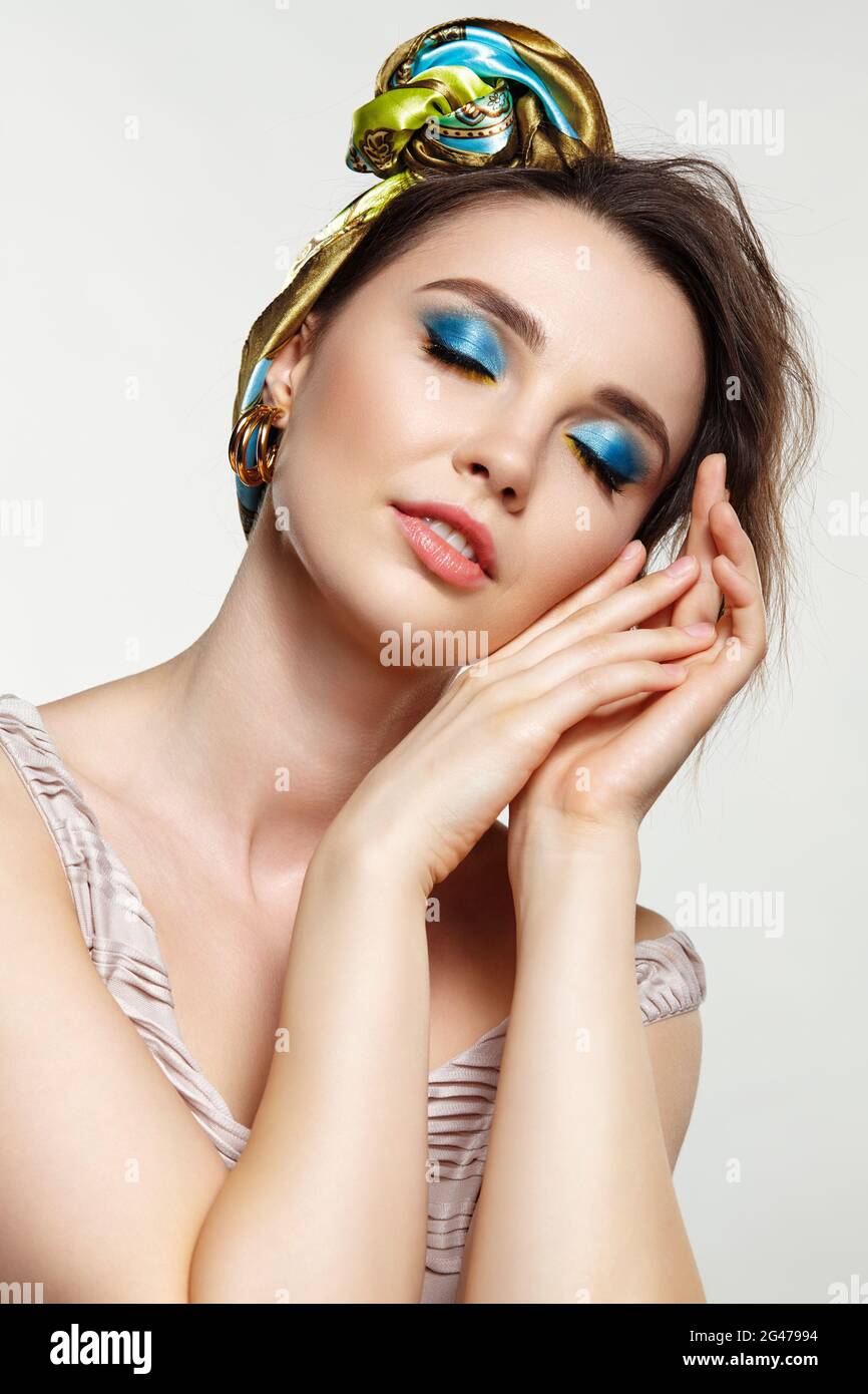 Porträt einer jungen Frau mit geschlossenen Augen. Weibchen posiert im Kopftuch mit der Hand im Gesicht. Stockfoto