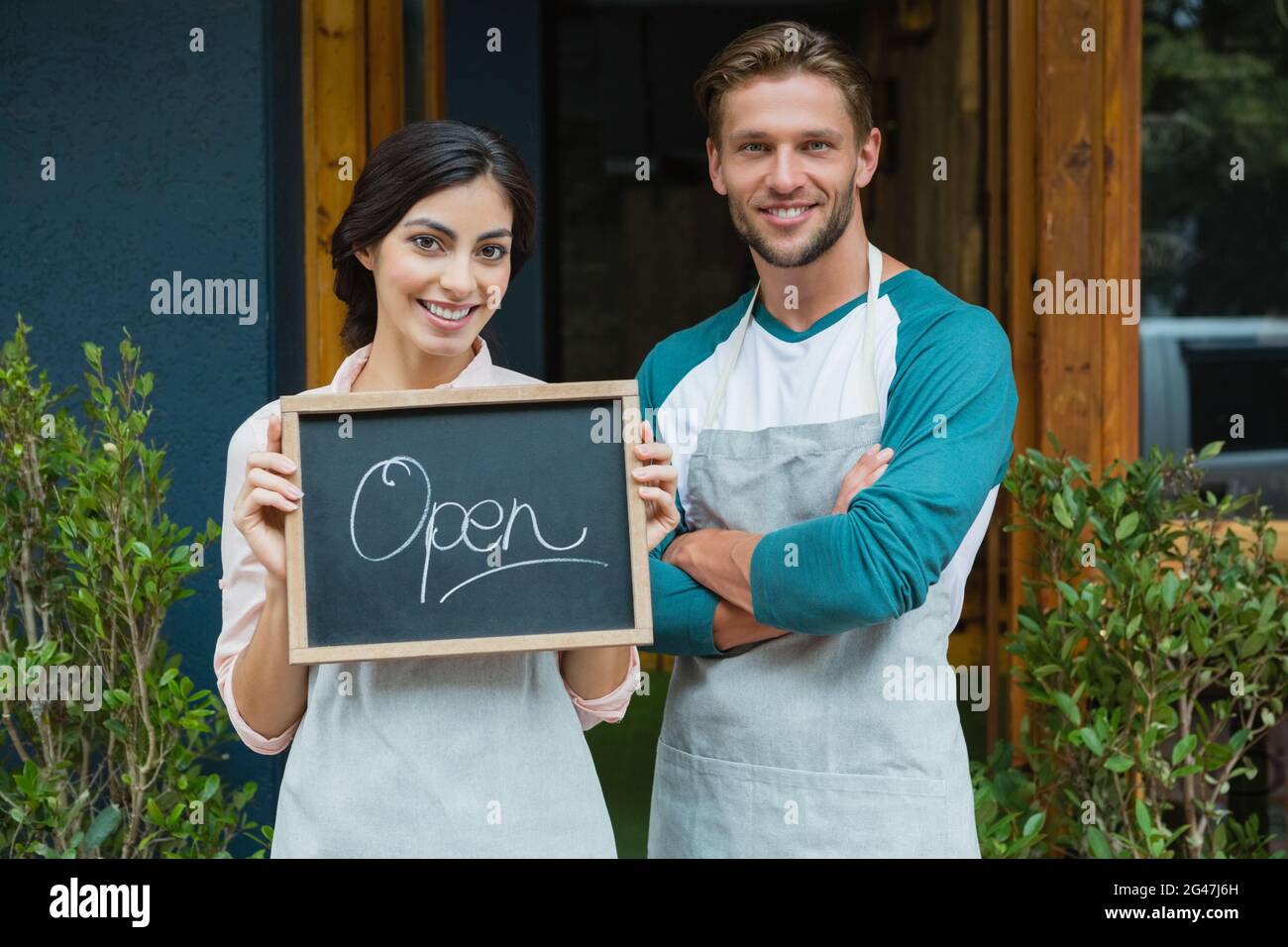 Porträt eines lächelnden Kellners und einer Kellnerin, die mit einer Tafel stehen Stockfoto