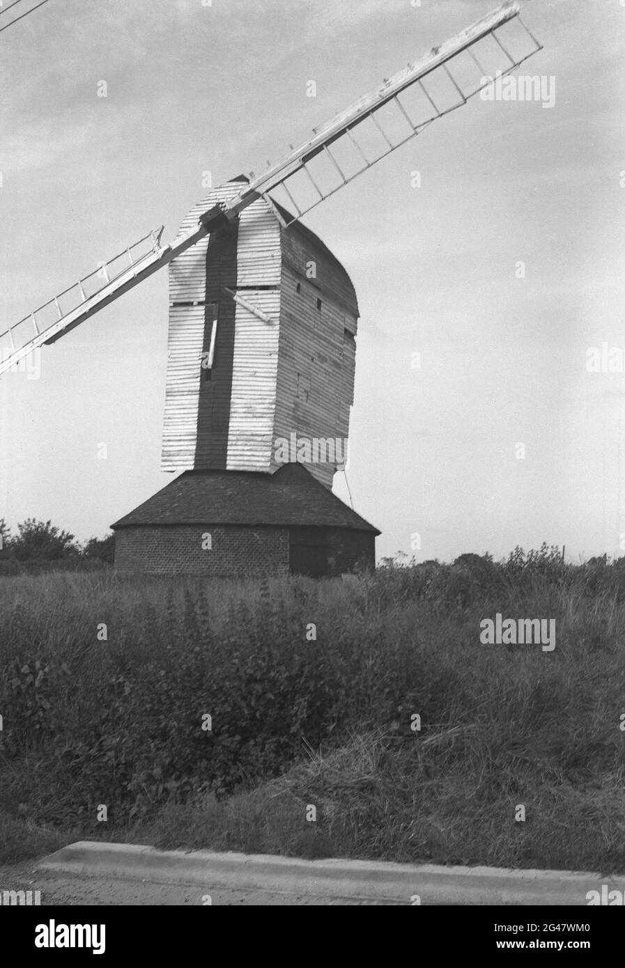 1954, historisch, Windmühle, Essex, England, VEREINIGTES KÖNIGREICH. Diese markanten Gebäude, die in verschiedenen Formen erhältlich sind, haben Klingen oder Flügel, einige davon auf Holzkonstruktionen, die hier zu sehen sind, über einem Stein- oder Ziegelgebäude, das den Strom aus dem Wind erzeugt, um Mais zu Mehl zu mahlen. Stockfoto