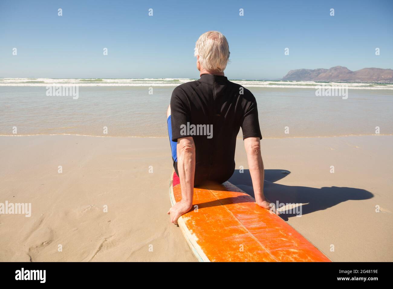 Rückansicht eines älteren Mannes, der auf dem Surfbrett sitzt Stockfoto