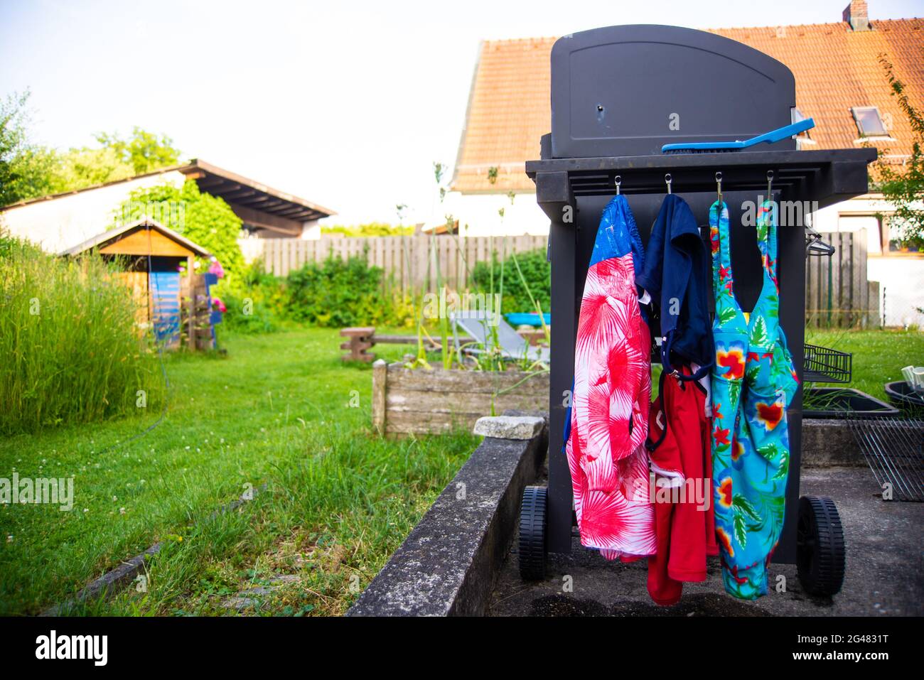 Drei Badeanzüge hängen zum Trocknen vom Grill ab Stockfoto