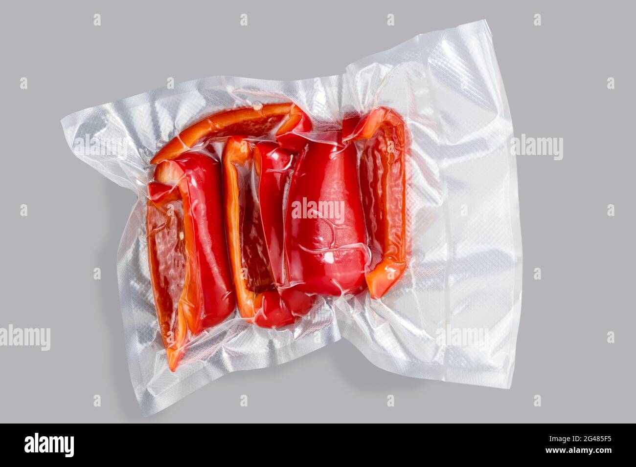 Rote Paprika in vakuumverpackter, versiegelter Verpackung zum Kochen mit Sous Vide, isoliert auf grauem Hintergrund Stockfoto