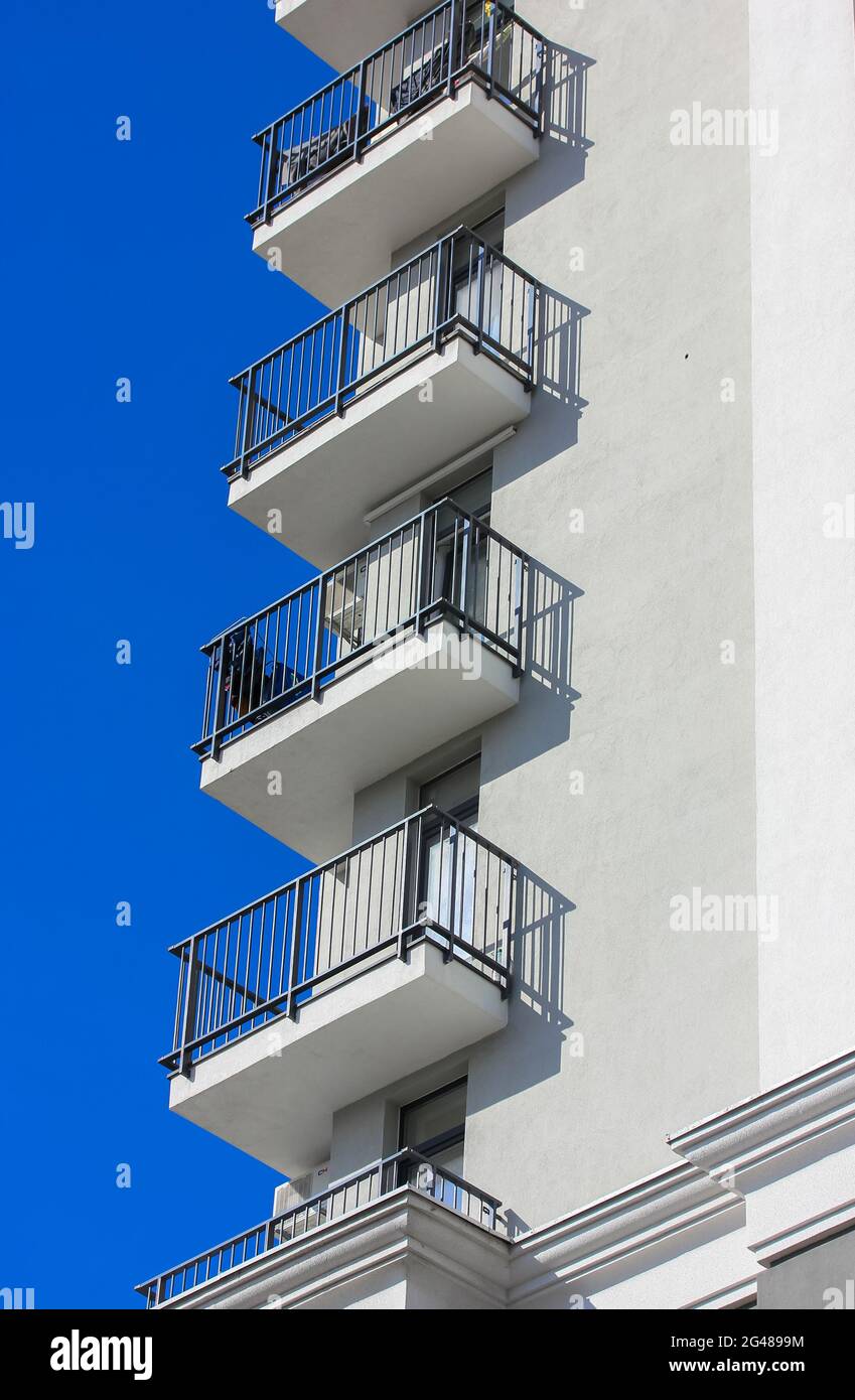 Das Äußere eines modernen Luxus-Apartmentgebäudes in der Stadt. Balkone eines neu gebauten Hauses mit schwarzen Metallgittern und kontrastierenden Schatten auf einem Su Stockfoto
