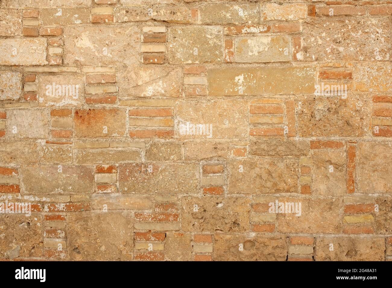 Die Backsteinmauer des alten Gebäudes im Hintergrund. Eine Wand aus Muschel. Sandsteinbausteine. Raue Textur einer Ziegelwand aus Sand und Stockfoto