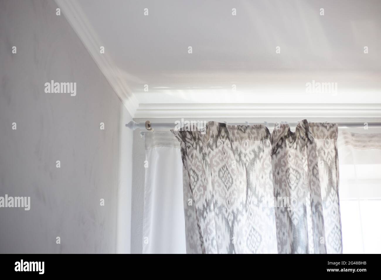 Graue Vorhänge hängen an den Vorhangringen im Schlafzimmer. Einrichtung für heimischen Komfort. Stockfoto
