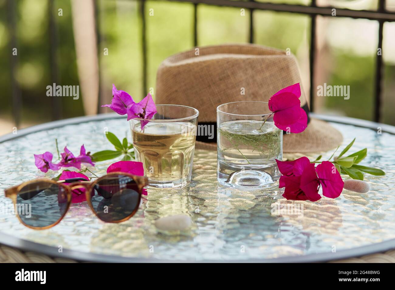 Kreative Sommer hausgemachte Cocktails aus der Nähe und rosa Blumen von Bougainvillea Dekorationen mit Sonnenschutz und Sommerhut. Sommertapete. Stockfoto