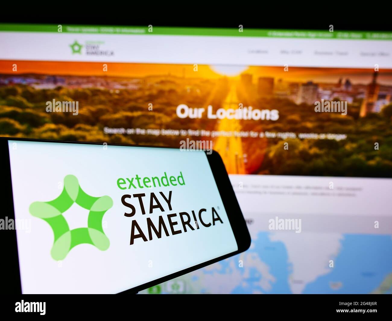 Person, die Mobiltelefon mit dem Logo der amerikanischen Apartmenthotelkette Extended Stay America Inc auf dem Bildschirm vor der Website hält. Konzentrieren Sie sich auf die Telefonanzeige. Stockfoto