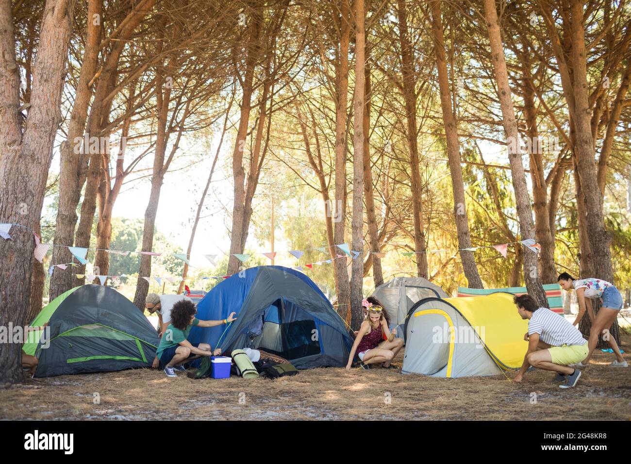 Freunde bauen auf dem Campingplatz farbenfrohe Zelte auf Stockfoto