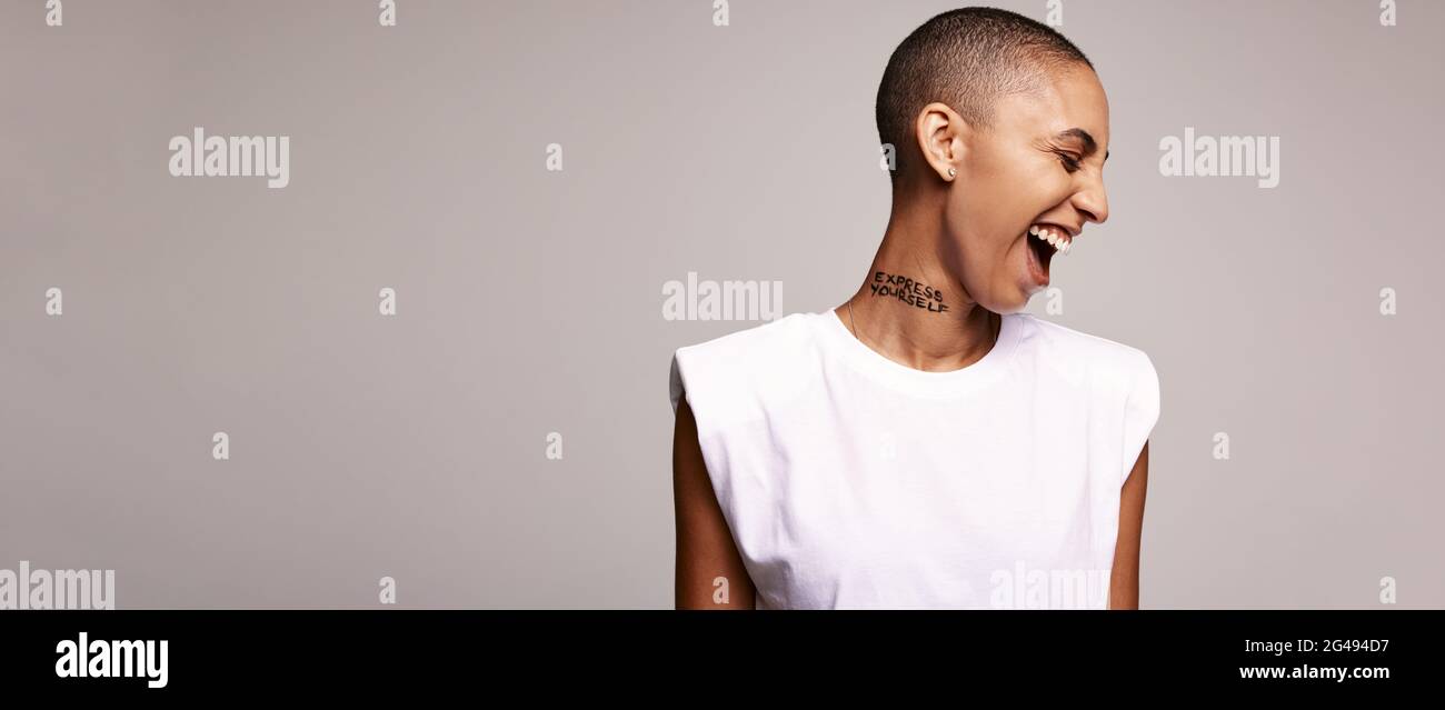 Aufgeregt Frau mit rasierten Kopf auf farbigem Hintergrund. Frau mit kurzen Haaren lächelt im Studio. Stockfoto