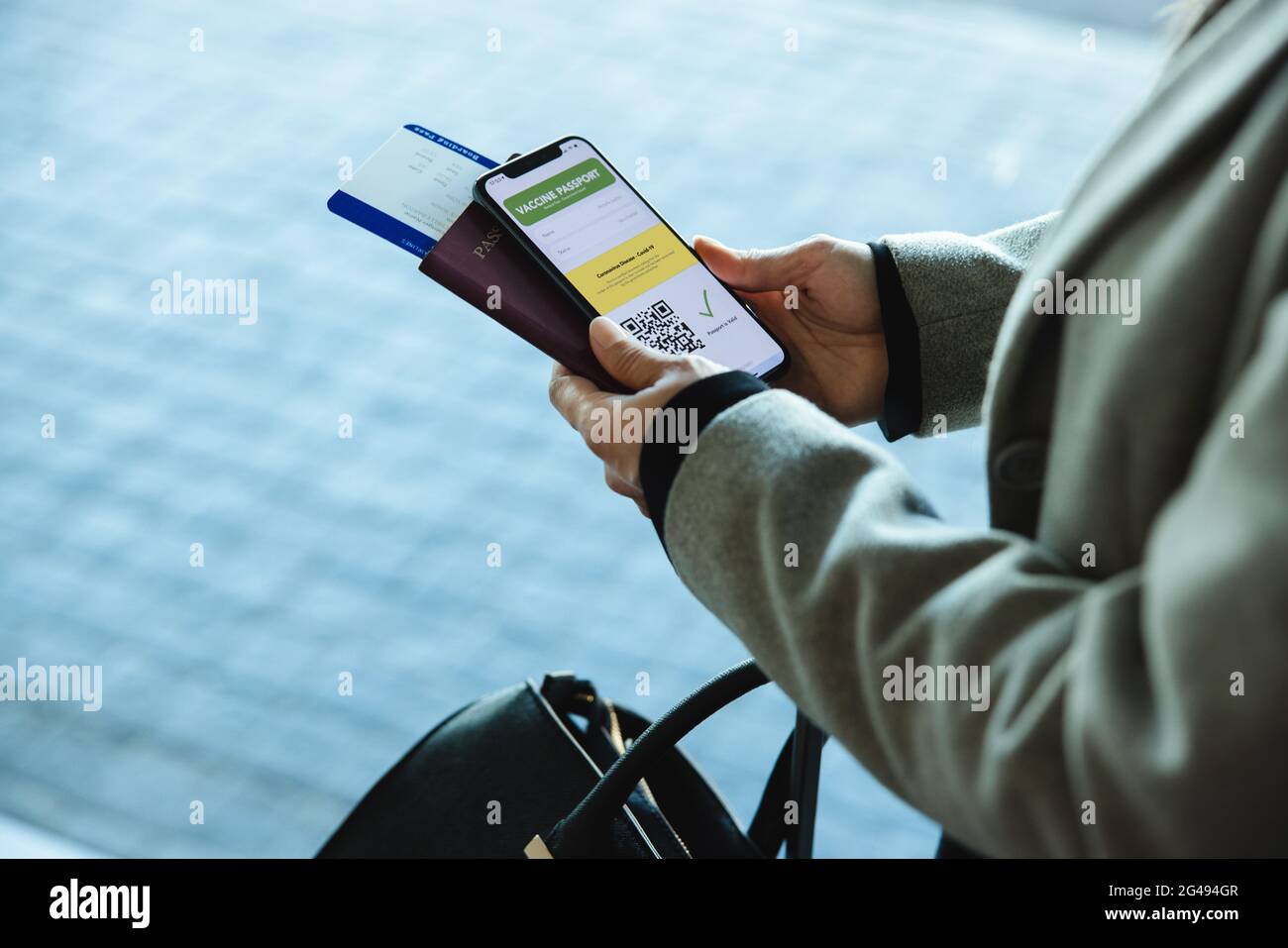 Über die Schulter einer weiblichen Reisenden am Flughafen mit Pass, Ticket und covid-19 Impfpass auf ihrem Handy. Frau, die mit ai reist Stockfoto