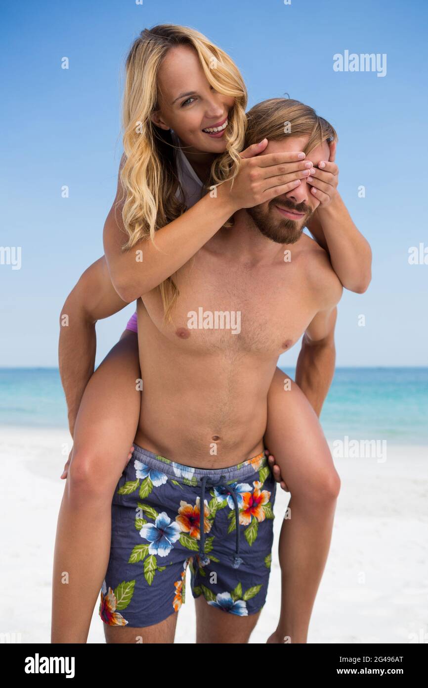 Mann Huckepack fröhliche Frau am Strand Stockfoto