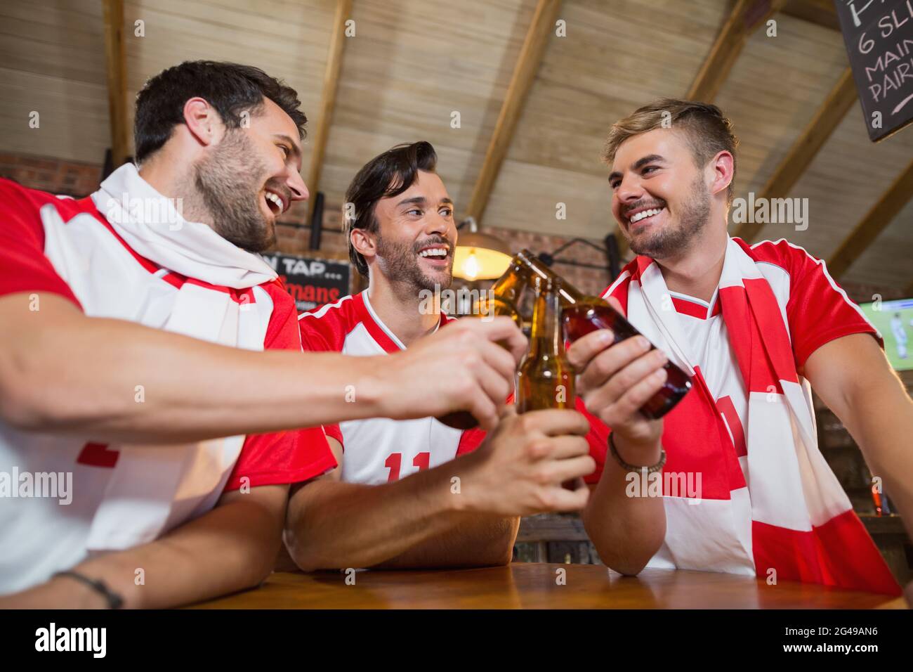 Fröhliche männliche Freunde, die Bierflaschen toasten Stockfoto
