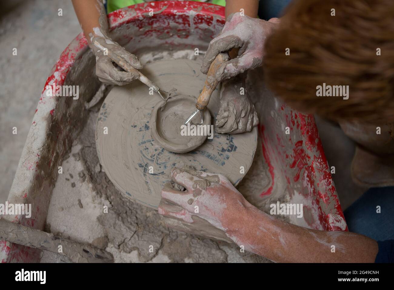 Männlicher Töpfer, der Mädchen beim Formen eines Tones hilft Stockfoto