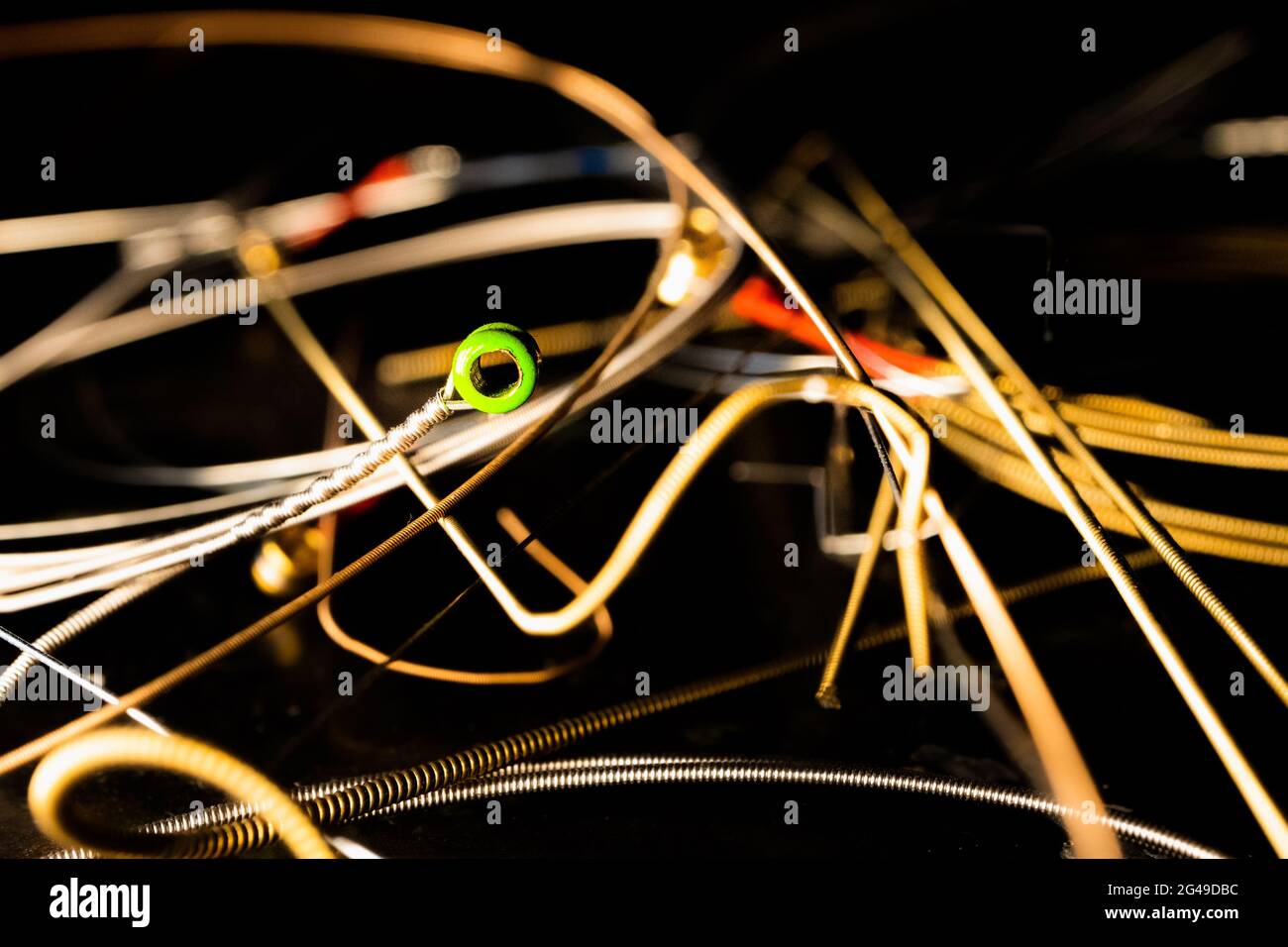 Nahaufnahme des Green Ball End auf der Gitarrensaite vor dem Stapel der verwendeten Bronze-Gitarrensaiten Stockfoto