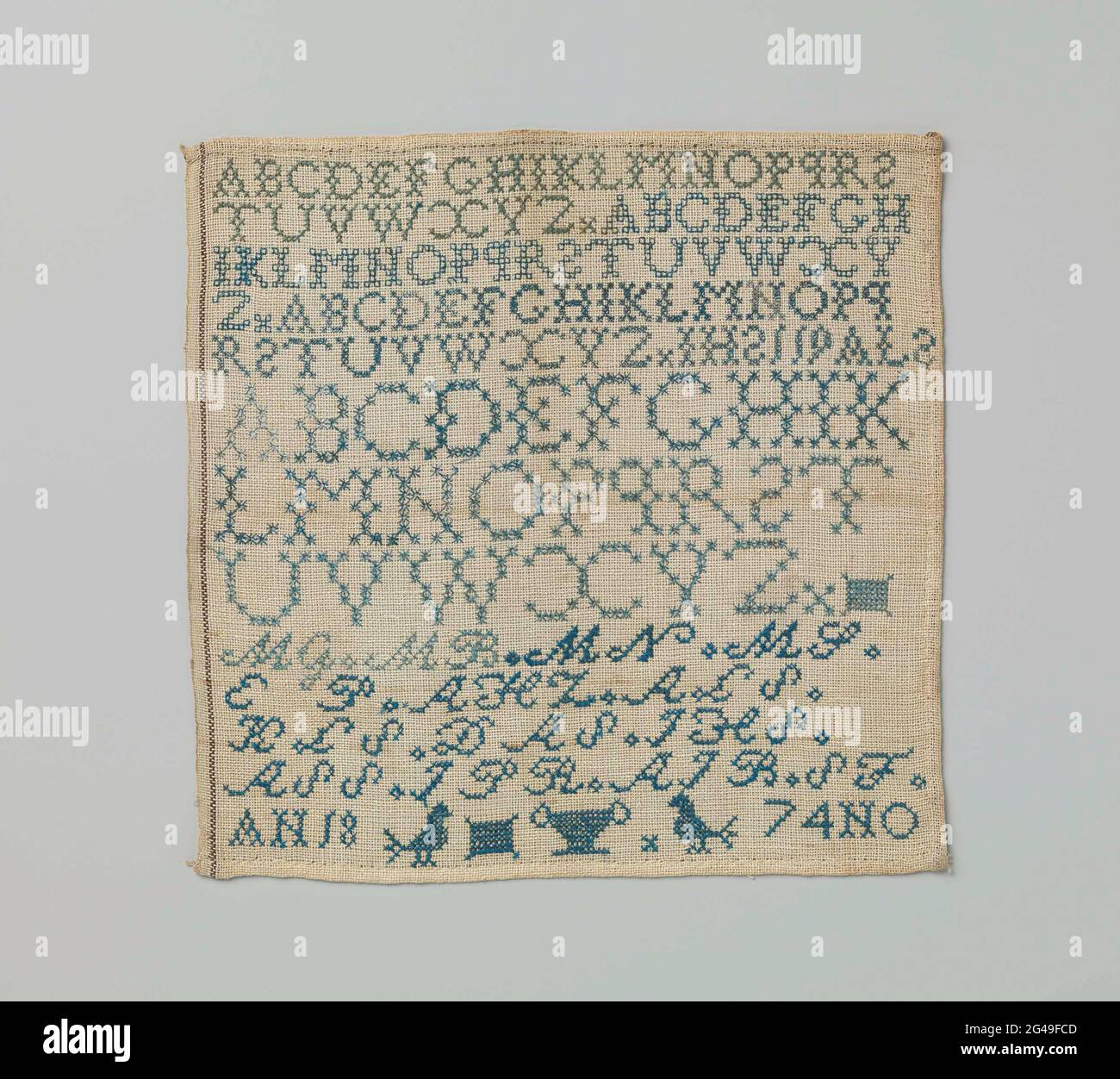 Merklap aus Seide auf Baumwolle. Merklap aus Seide auf Baumwolle. Die Stickerei besteht aus den Initialen MG, MB, MN, MS, dem Alphabet, Zwei Vögel, eine Vase und ein Rechteck. Die Runde ist datiert: 1874. Stockfoto