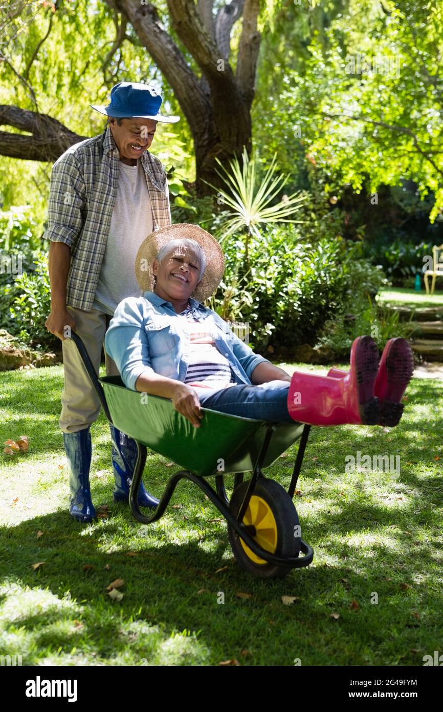 Älterer Mann, der Frau die Schubkarre zum Fahren gibt Stockfoto