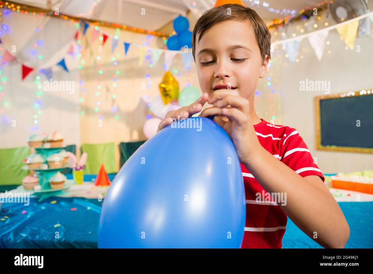 Niedlicher Junge hält blauen Ballon während der Geburtstagsfeier Stockfoto