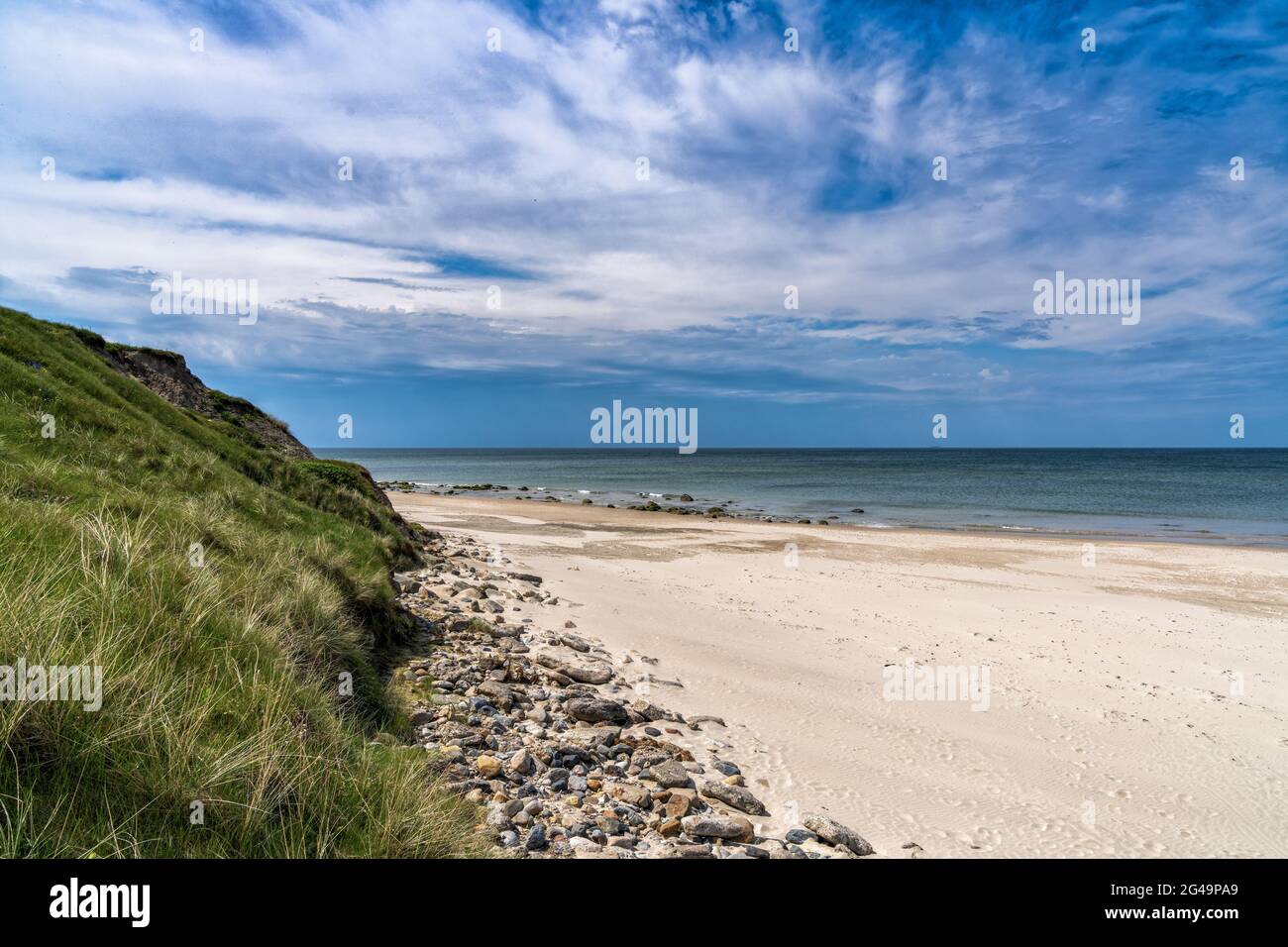 Ein wunderschöner weißer Sandstrand mit hohen grasbewachsenen Sanddünen dahinter Stockfoto