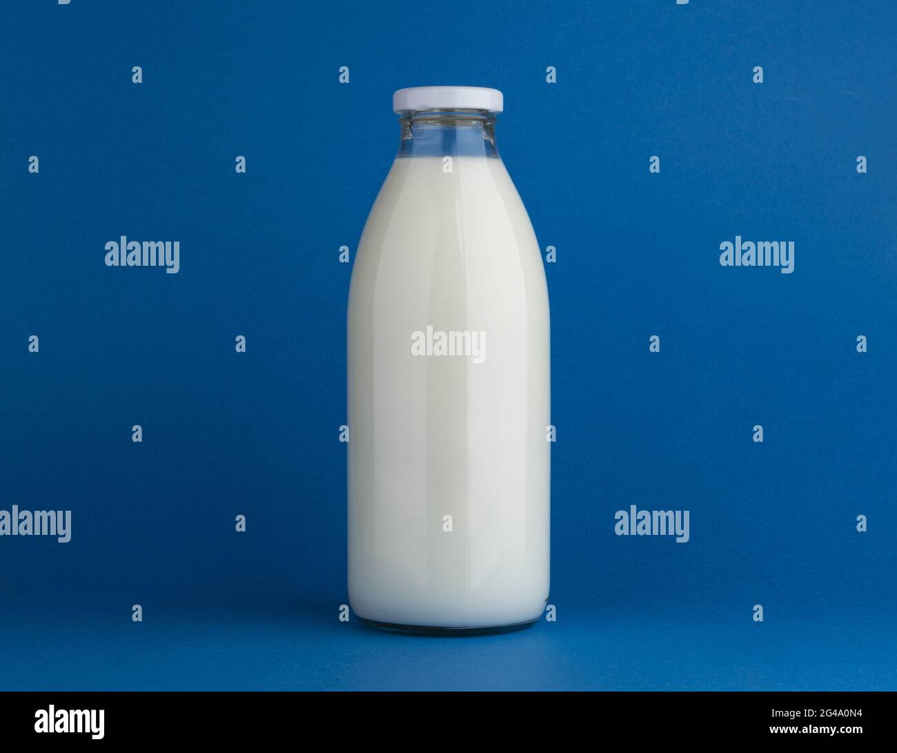 Glasmilchflasche auf blauem Hintergrund verspotten Stockfoto