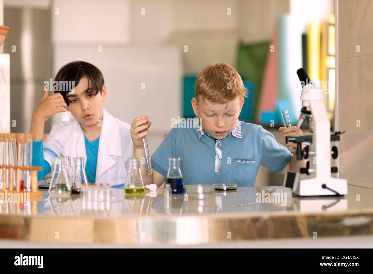 Zwei Laborassistenten Kinder führen Experimente mit farbigen Flüssigkeiten durch Stockfoto