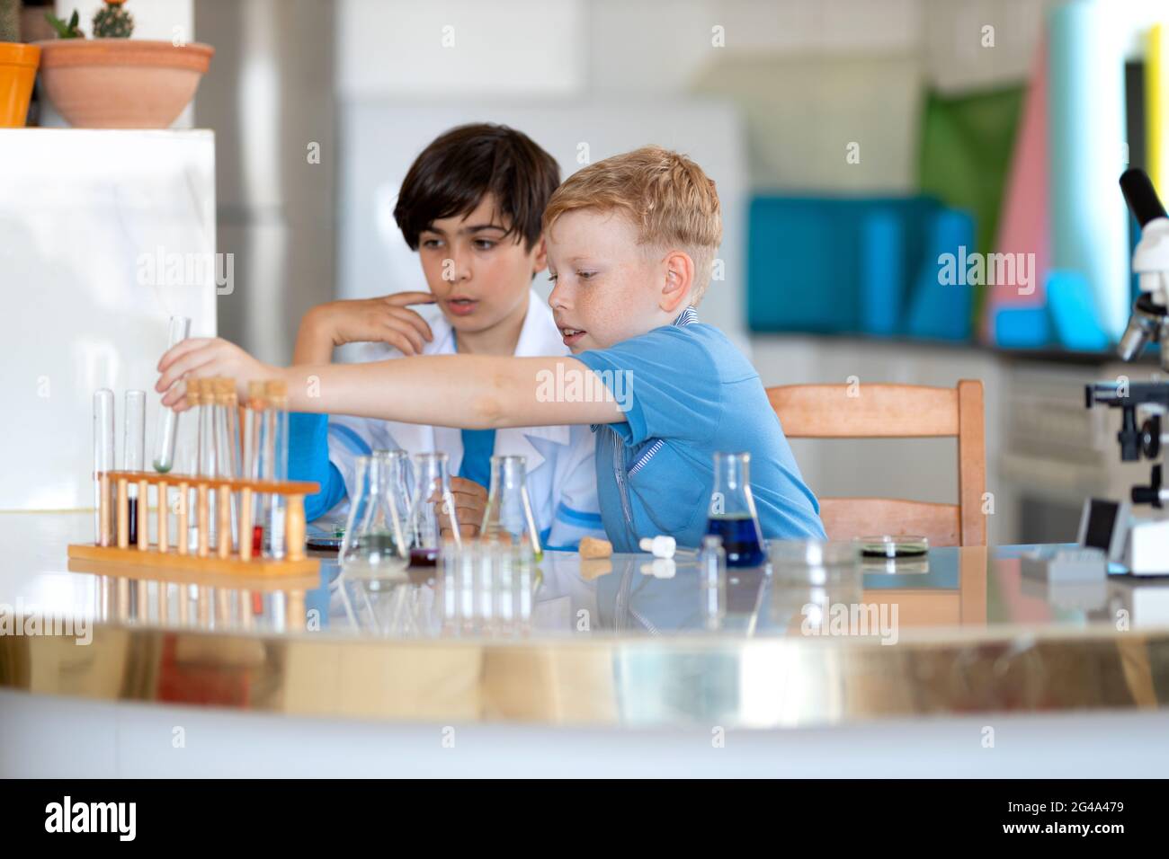 Zwei Laborassistenten Kinder führen Experimente mit farbigen Flüssigkeiten durch Stockfoto