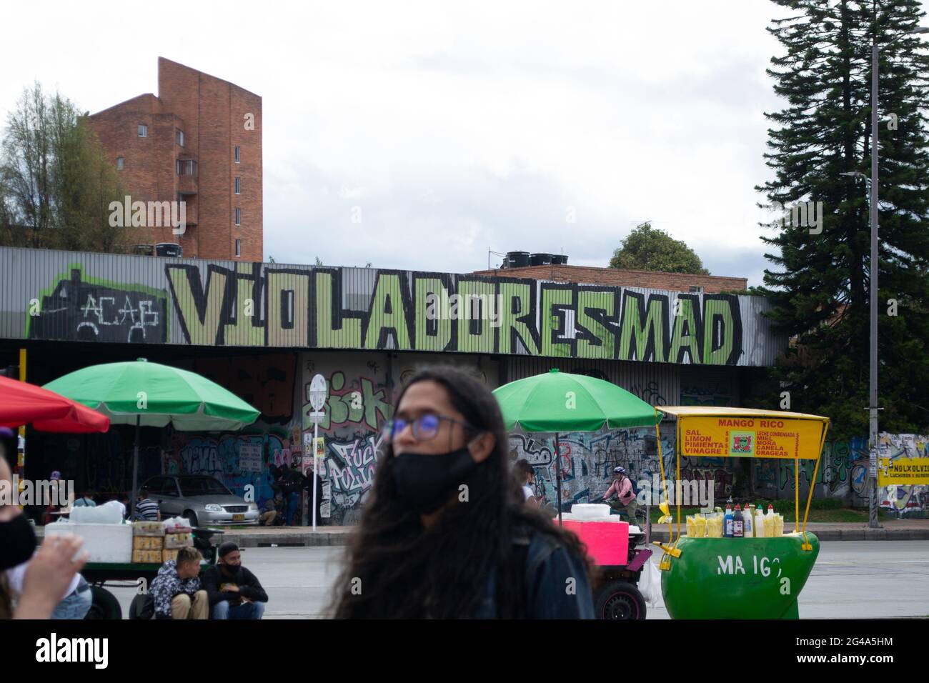 Ein Protestler vor einem Graffiti, das die Polizeigewalt bei regierungsfeindlichen Demonstrationen in Bogota, Kolumbien, am 19. Juni 2021 kritisiert Stockfoto