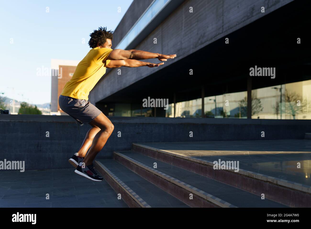 Schwarzer Mann tut Kniebeugen mit Springen auf einem Schritt. Stockfoto
