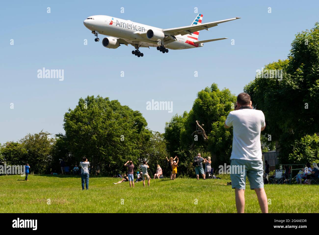 Das Flugzeug der American Airlines 777, das im Finale ansteht, landet am Flughafen London Heathrow, Großbritannien, über Enthusiasten, die sich in einem Park darunter befinden Stockfoto