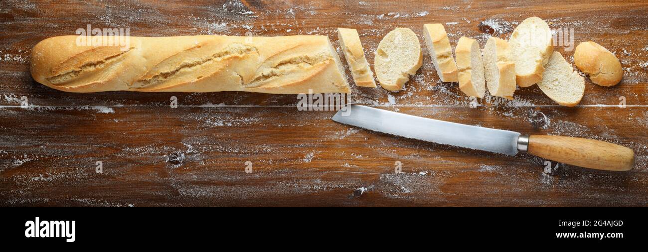 Brot, Messer und geschnittenes Baguette auf Holzhintergrund, Draufsicht, Platz für Text. Stockfoto