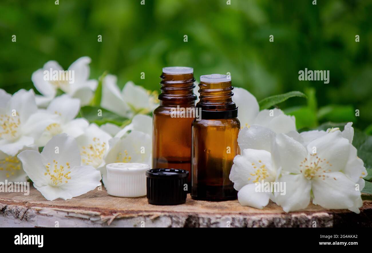 Ätherisches Öl und Jasminblüten auf einem hölzernen Hintergrund. Kosmetische Verfahren. Stockfoto