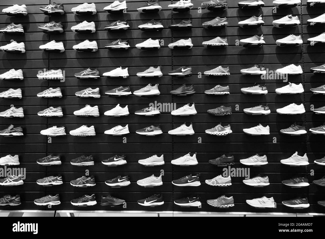Schwarz-Weiß-Bild Shop Display von vielen Sportschuhen an der Wand. Blick auf eine Schuhwand im Laden. Moderne, neue, stylische Sneaker Laufschuhe Stockfoto