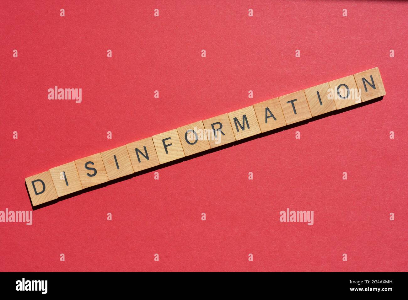 Desinformation, Wort in Holzalphabetbuchstaben isoliert auf rotem Hintergrund mit Kopierraum Stockfoto