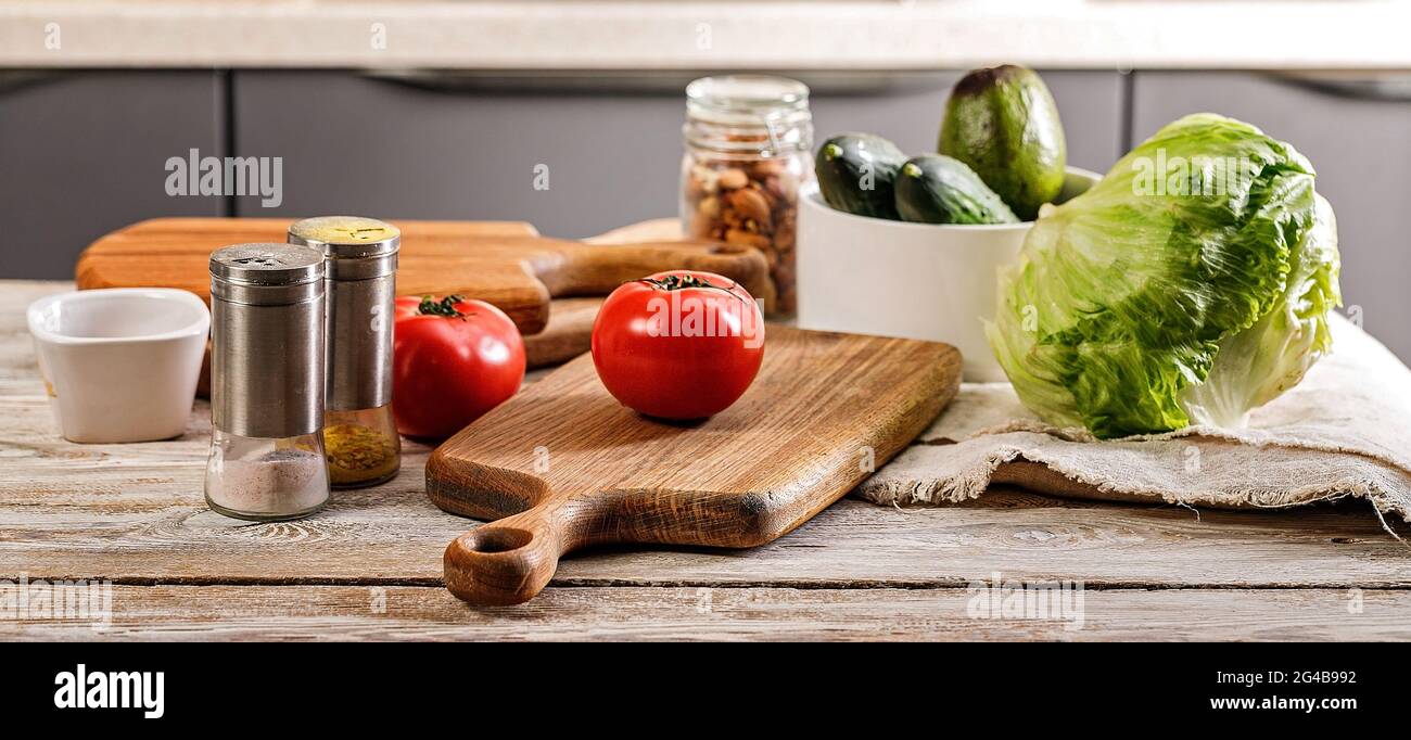 Lebensmittelbanner. Leckeres und gesundes Gemüse. Küchenzubehör. Schneiden von Holzbrettern und Utensilien. Reife Tomaten, frische Gurken und knuspriges Eis Stockfoto