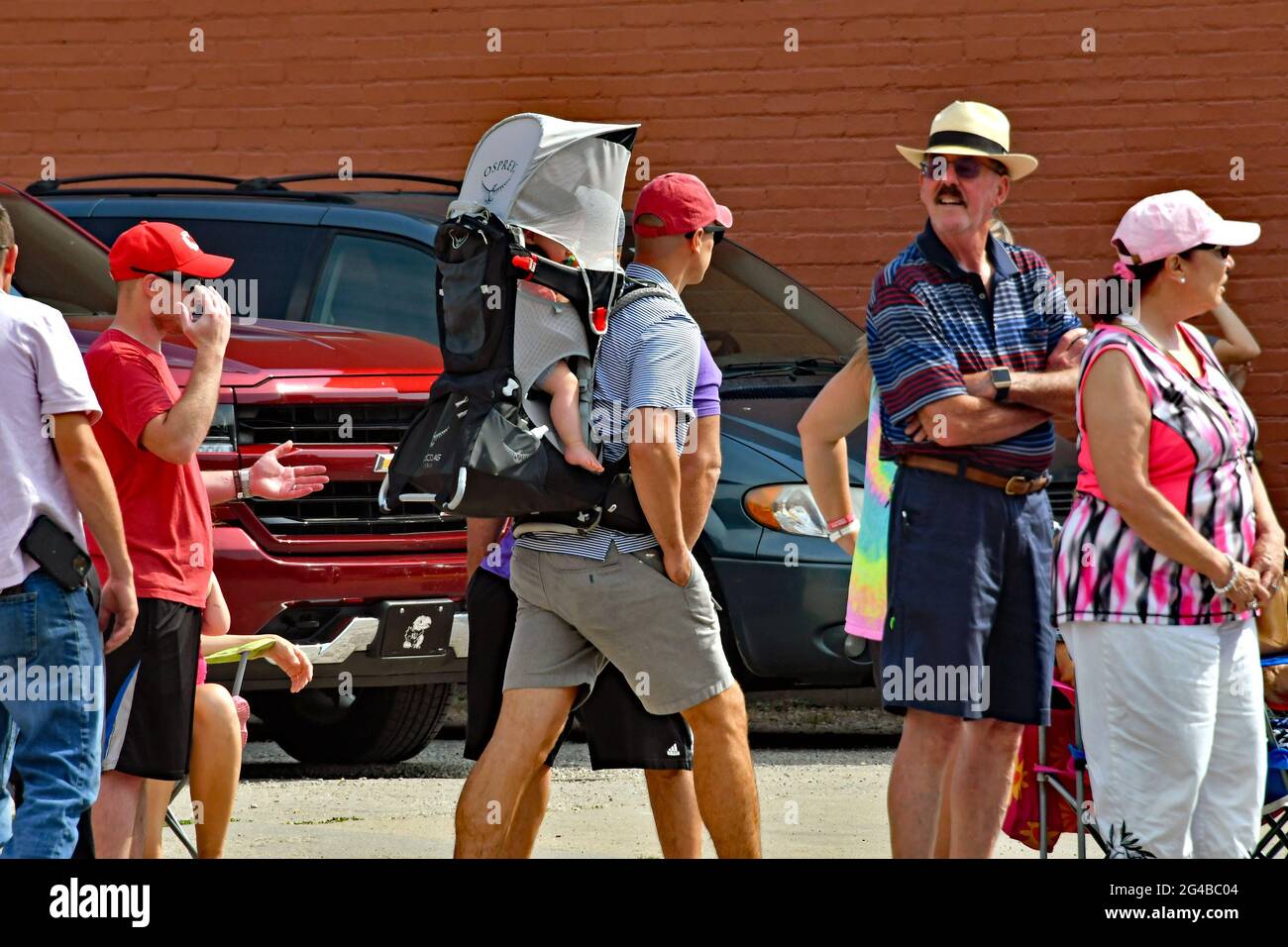 Der lokale Dade trägt sein Kind im Rucksack, als sich die Menge versammelt, die auf den Beginn der Parade der Council Grove Washungas Days am 19. Juni 2021 wartet. Kredit: Mark Reinstein/MediaPunch Stockfoto