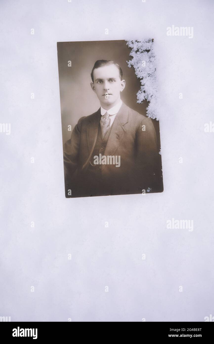 Authentisches Vintage-Portraitfoto des frühen 20. Jahrhunderts von einem jungen Mann im Anzug, der im Schnee liegt. Konzept von Einsamkeit, Einsamkeit, Vintage, Nostalgie Stockfoto