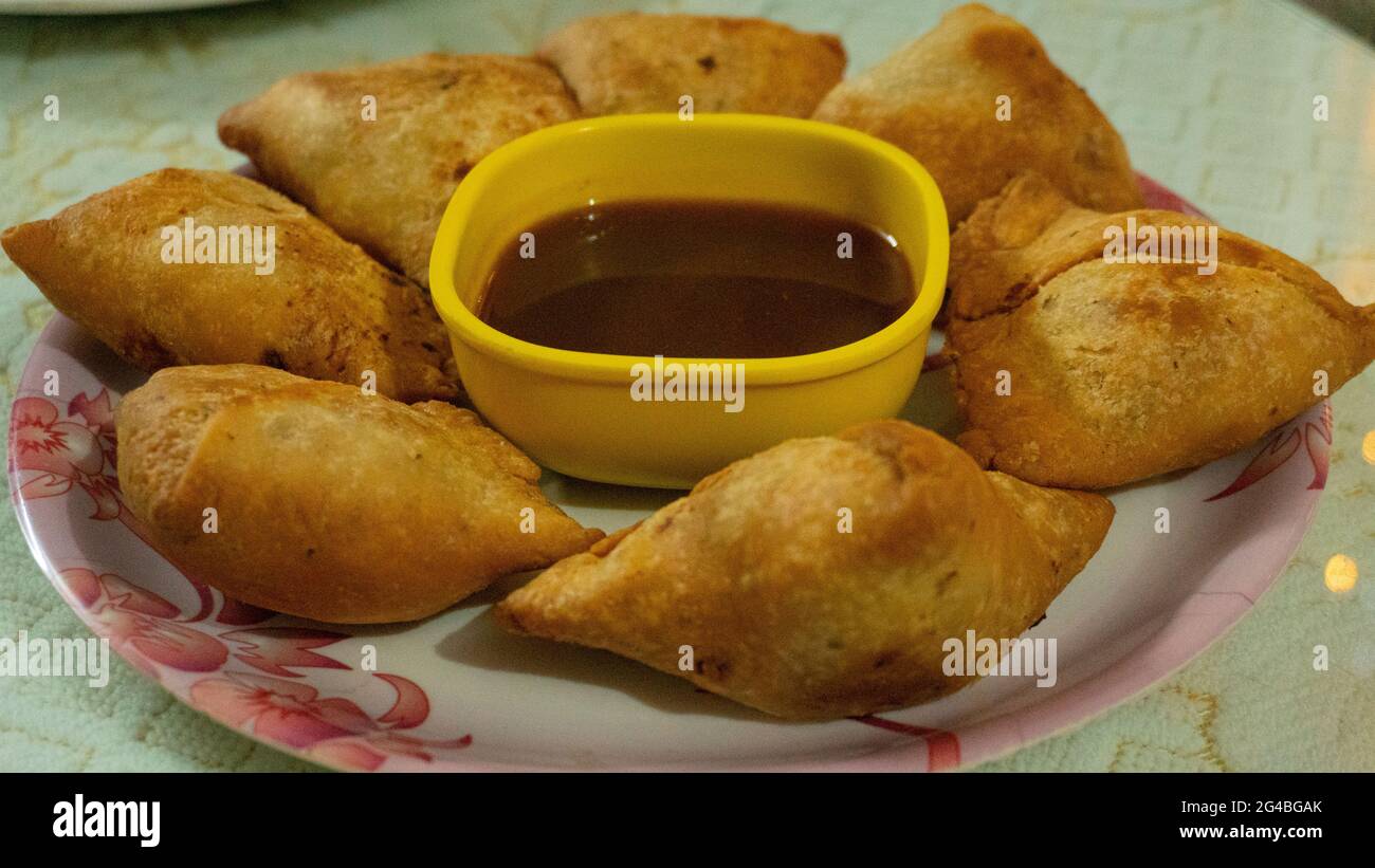 Dies ist ein indisches Gericht namens Samosa, das auf einem weißen Teller mit Sauce serviert wird Stockfoto