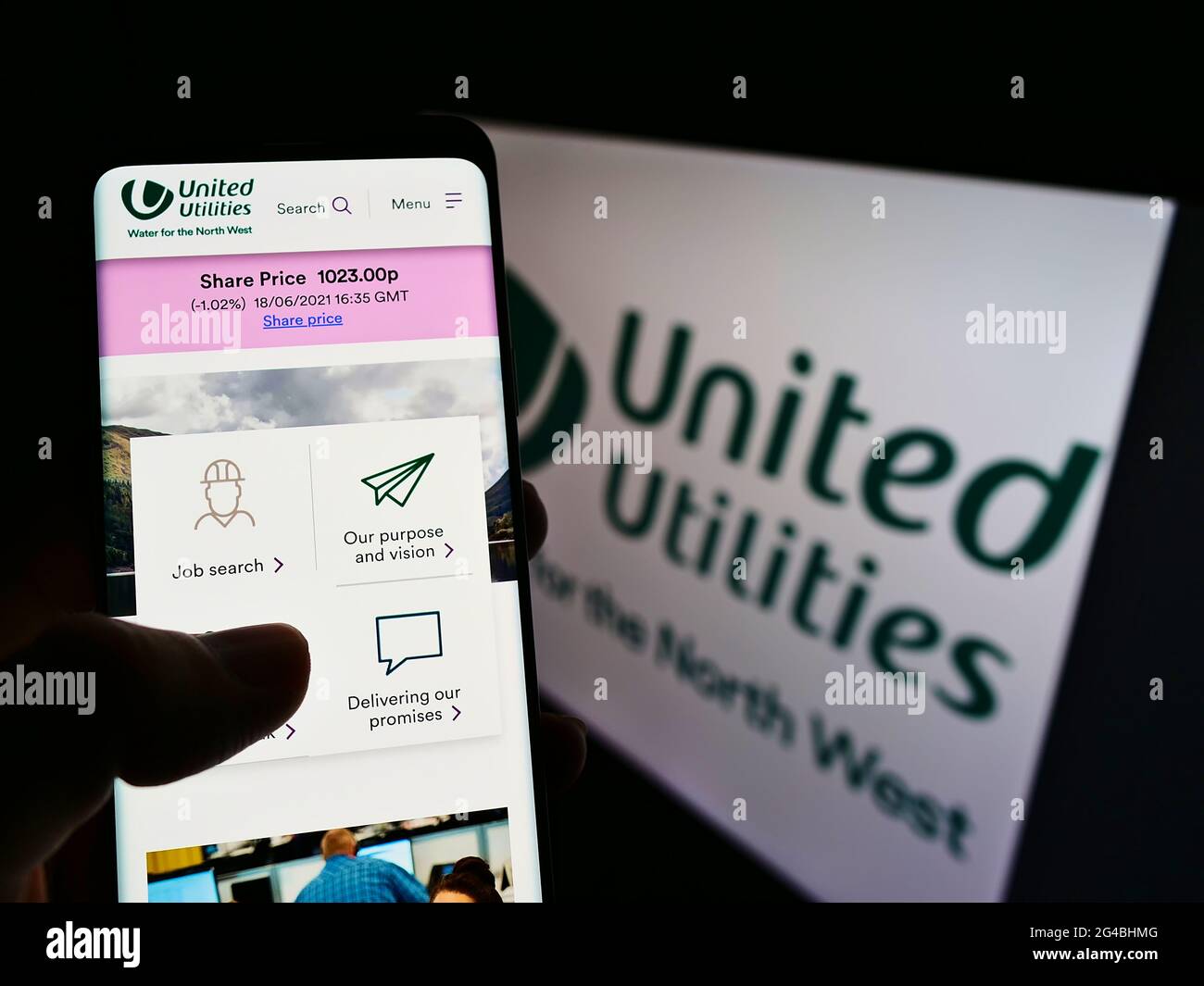 Person mit Smartphone und Website des britischen Wasserunternehmens United Utilities Group plc auf dem Bildschirm mit Logo. Konzentrieren Sie sich auf die Mitte des Telefondisplays. Stockfoto