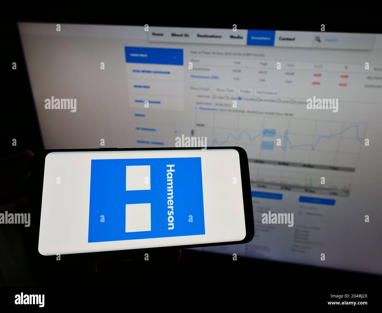 Person mit Mobiltelefon und Logo des britischen Immobilienentwicklungsunternehmens Hammerson plc auf dem Bildschirm vor der Webseite. Konzentrieren Sie sich auf die Telefonanzeige. Stockfoto