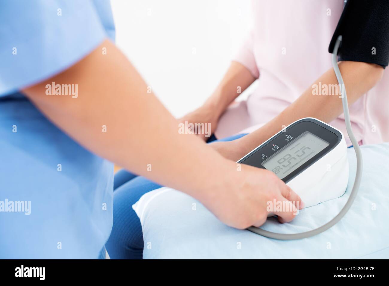 Die junge Frau lässt ihren Blutdruck von einer Krankenschwester, einem Arzt oder einem Gesundheitsgast überprüfen. Herzgesundheit. Digitaler Blutdruckmessgerät. Stockfoto