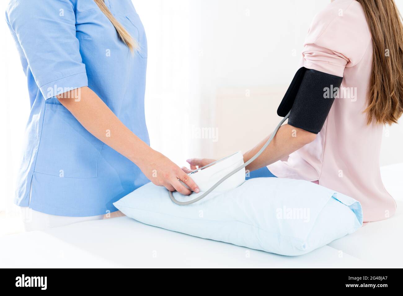 Die junge Frau lässt ihren Blutdruck von einer Krankenschwester, einem Arzt oder einem Gesundheitsgast überprüfen. Herzgesundheit. Digitaler Blutdruckmessgerät. Stockfoto