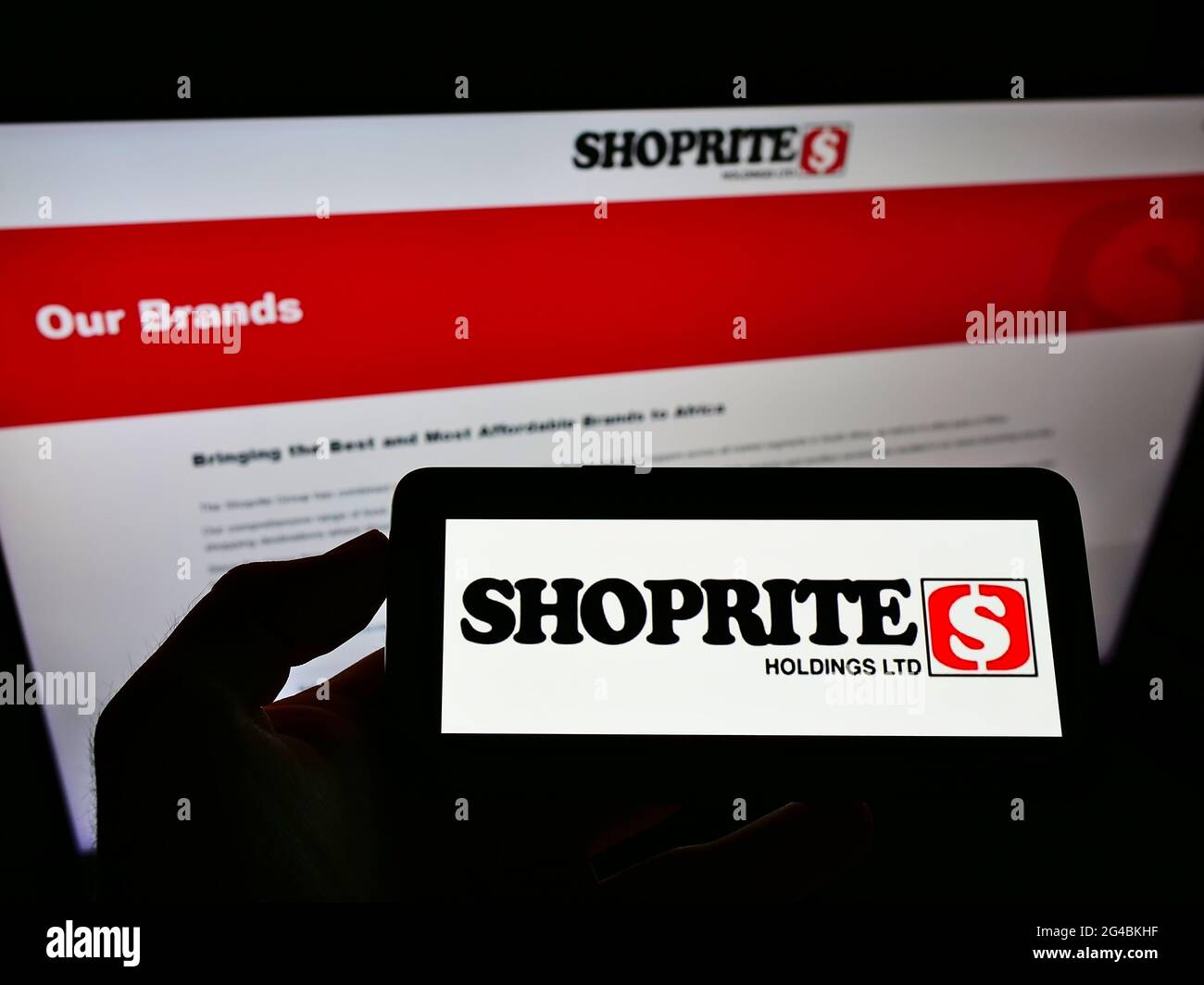 Person, die das Mobiltelefon mit dem Logo des südafrikanischen Einzelhändlers Shoprite Group of Companies auf dem Bildschirm vor der Webseite hält. Konzentrieren Sie sich auf die Telefonanzeige. Stockfoto