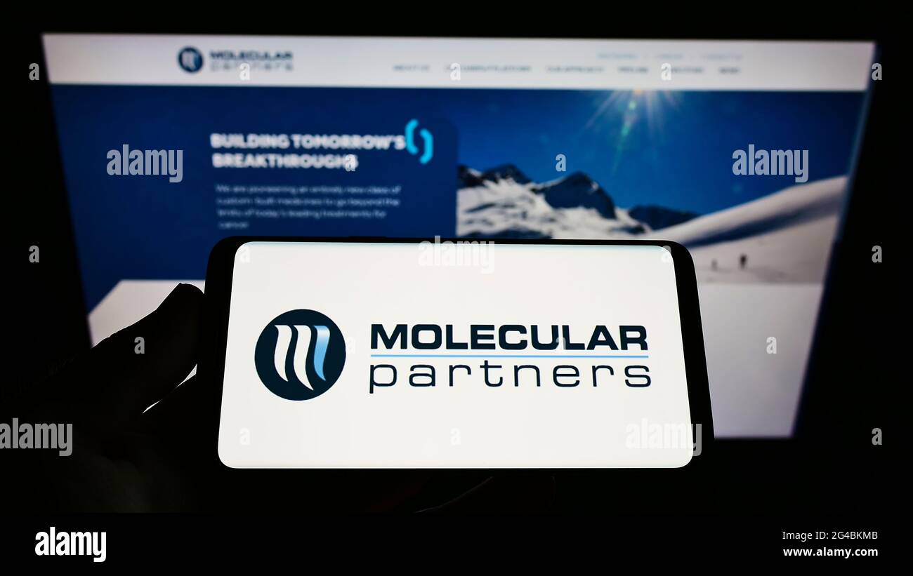 Person mit Mobiltelefon und Logo des Schweizer Biopharmaunternehmens Molecular Partners AG auf dem Bildschirm vor der Webseite. Konzentrieren Sie sich auf die Telefonanzeige. Stockfoto