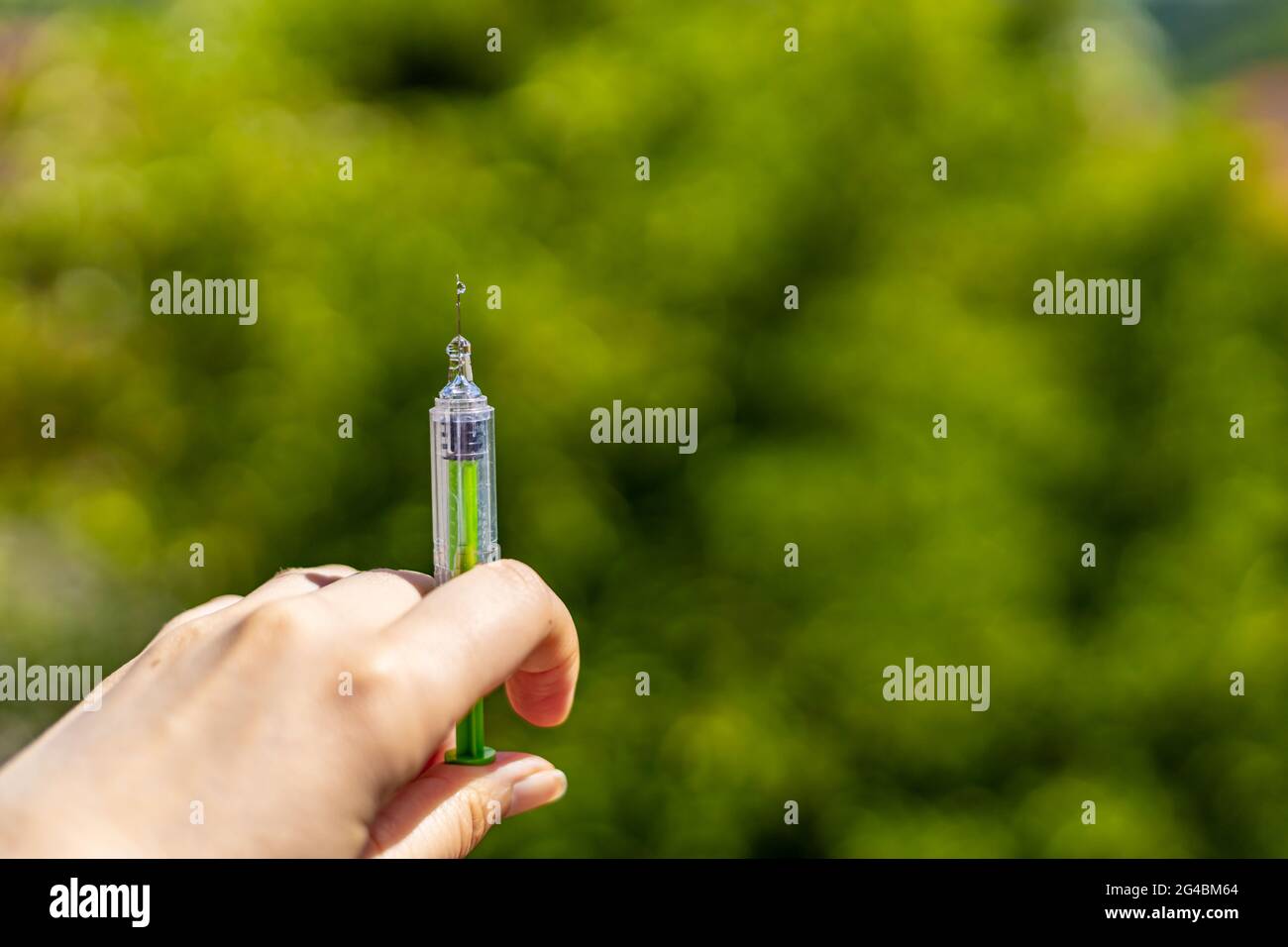 Hand halten Spritze mit Tropfen auf der Nadel Stockfoto