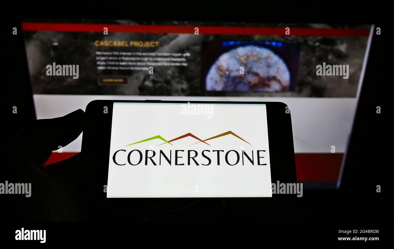 Person mit Mobiltelefon und Logo des Bergbauunternehmens Cornerstone Capital Resources Inc. Auf dem Bildschirm vor der Webseite. Konzentrieren Sie sich auf die Telefonanzeige. Stockfoto
