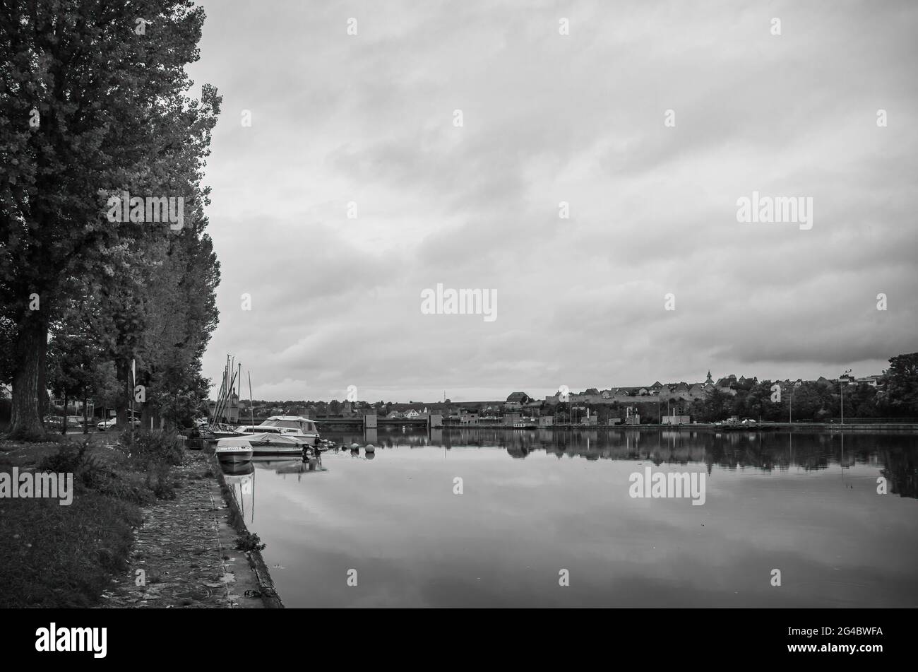 Lauffen am Neckar, Baden-Württemberg, Deutschland: Staumauer und Schleuse im Neckar mit der Silhouette der mittelalterlichen Stadtmauer im Hintergrund. Stockfoto