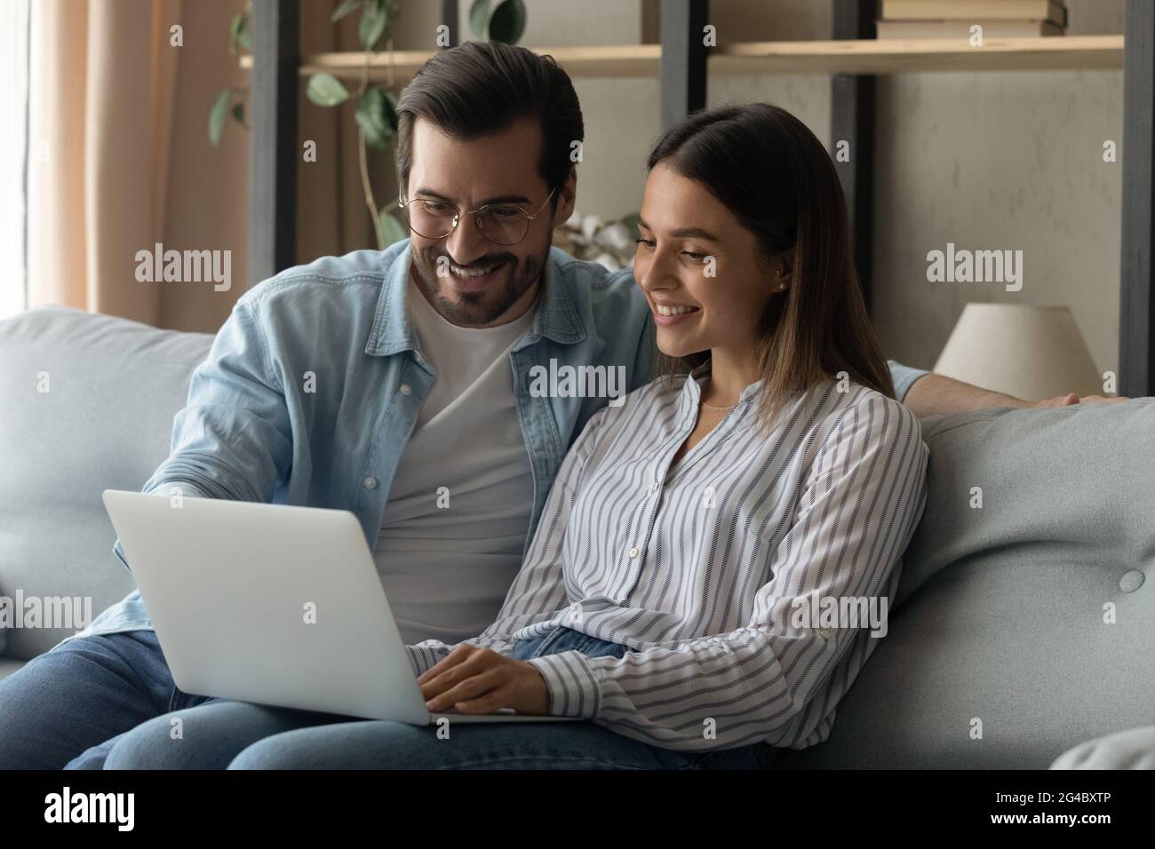 Entspanntes, glückliches junges Familienpaar, das zu Hause einen Computer benutzt. Stockfoto