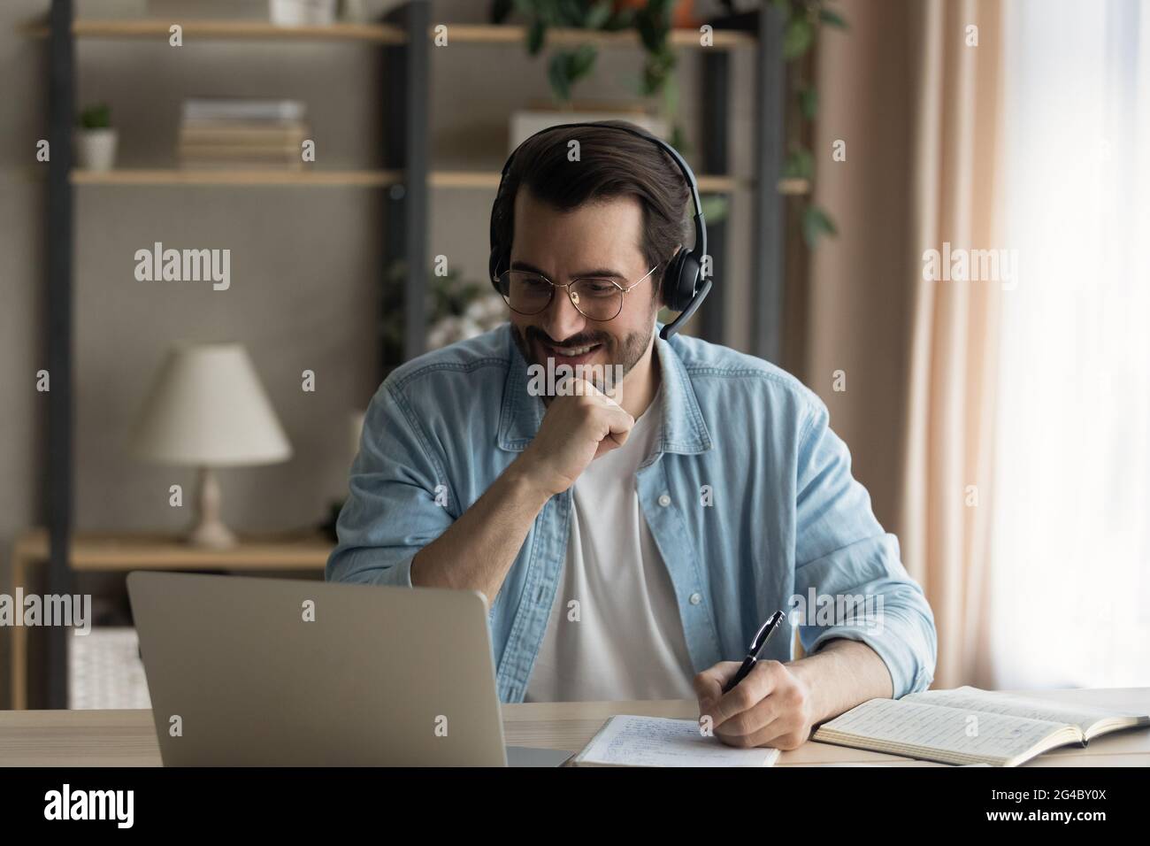 Glücklicher junger Mann hört pädagogische Online-Vortrag auf Computer. Stockfoto