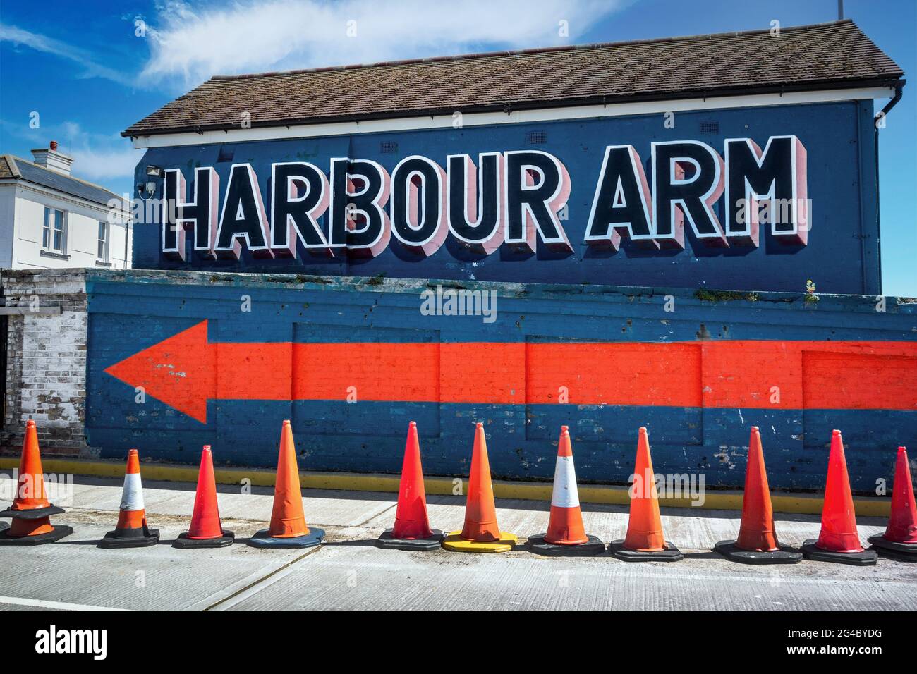 Hafenarm-Schild mit einem großen orangefarbenen Pfeil an einer hellblauen Wand, Folkestone Harbour Kent Stockfoto