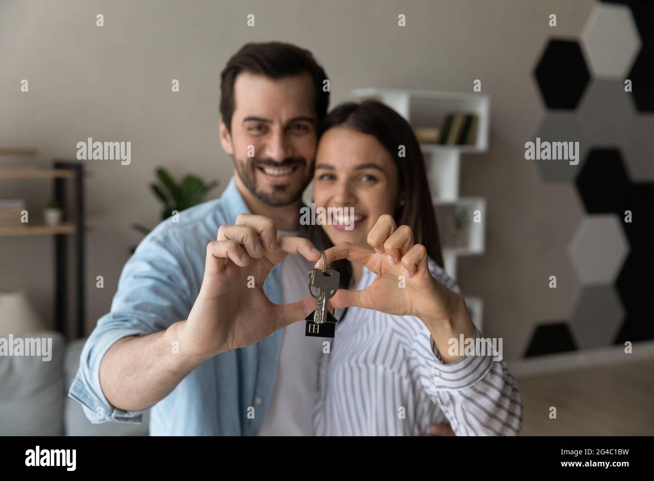 Glückliches aufrichtiges junges Familienpaar, das die Schlüssel zur Kamera zeigt. Stockfoto